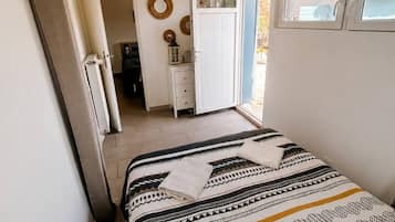 A bedroom with a bed, a window, and a door leading to a bathroom.