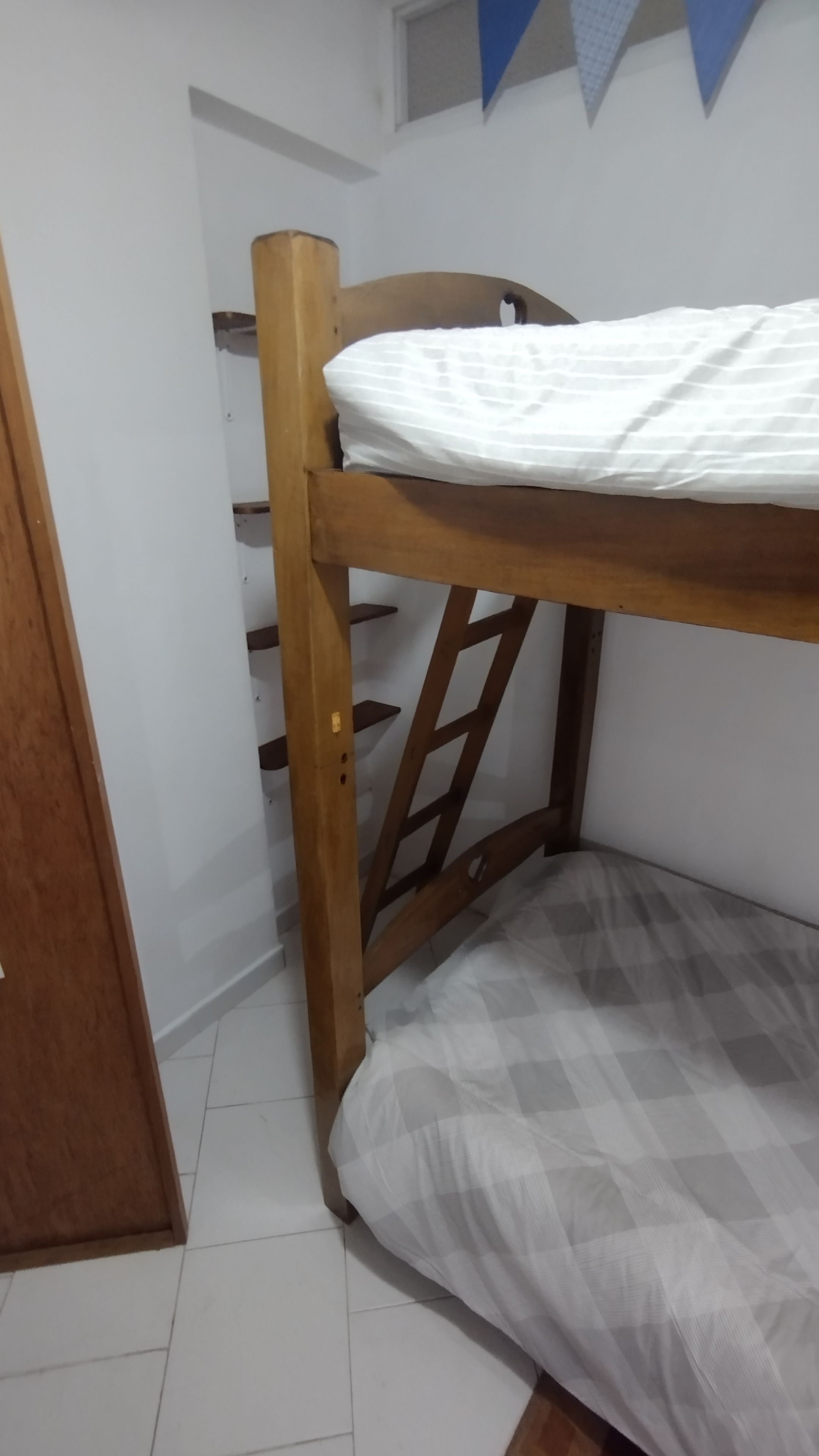 A bunk bed with a wooden frame and a checkered mattress.