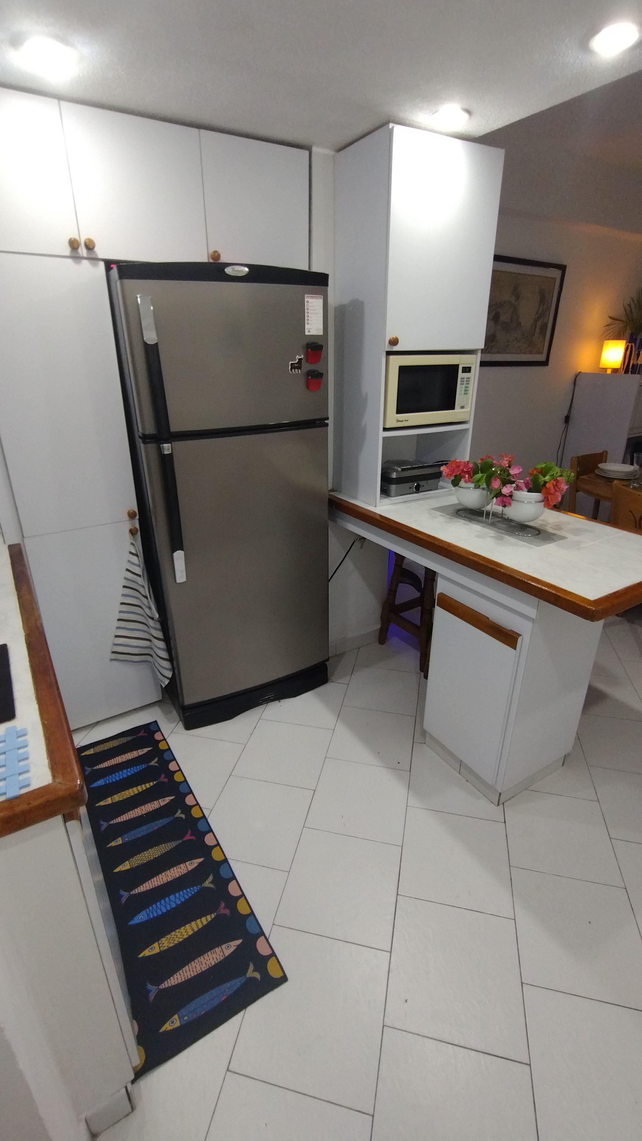 A compact kitchen with a refrigerator, microwave, and a small island with a sink.