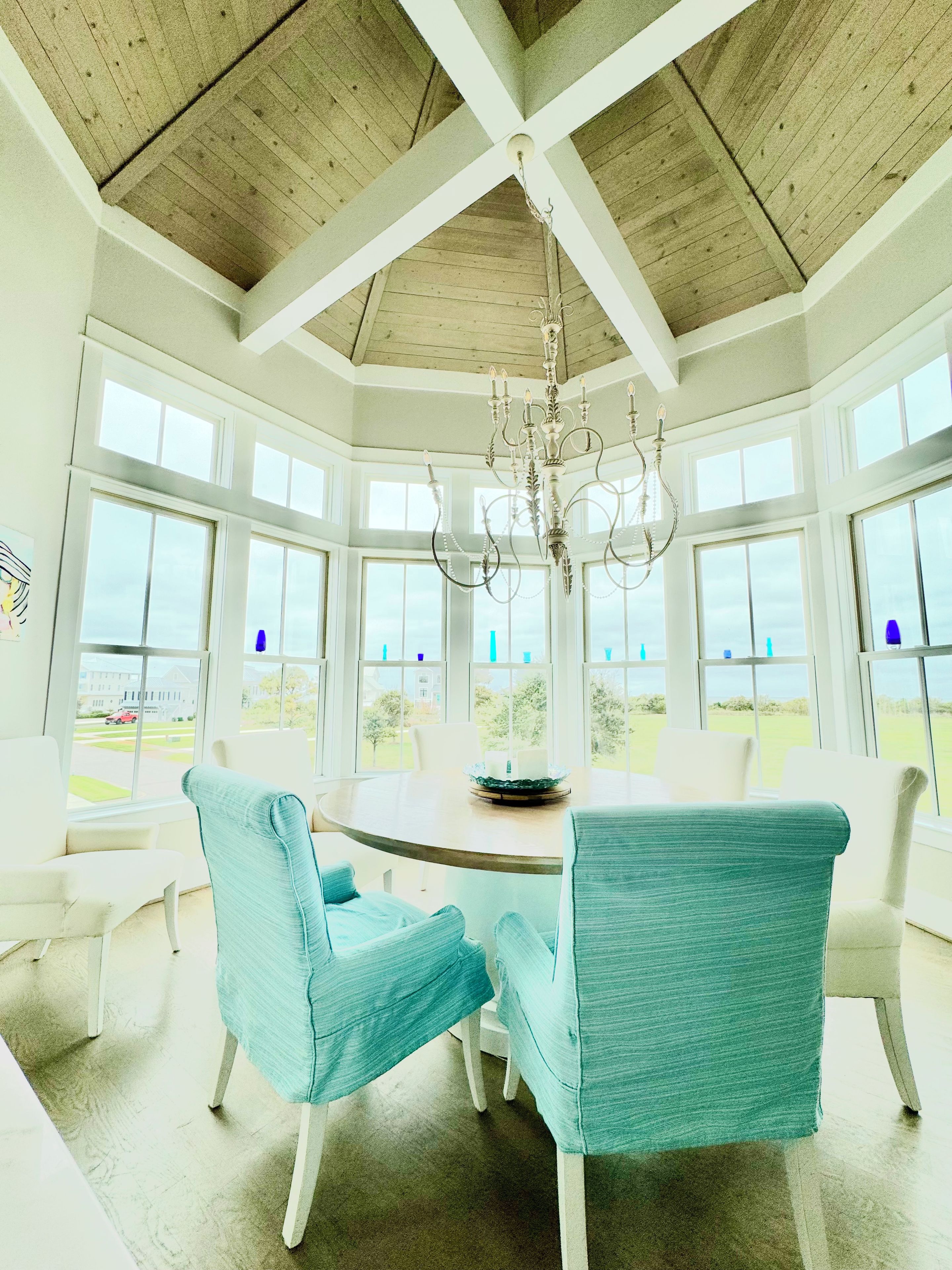 A dining area with a round table, four chairs, and a chandelier.