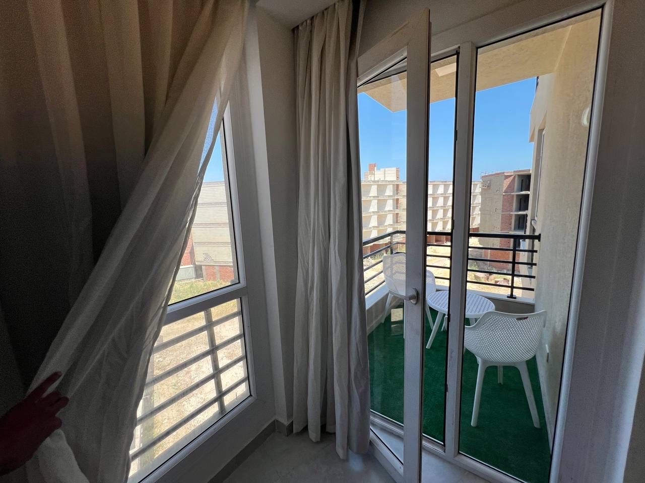 Ein Balkon mit Blick auf Gebäude, ein weißer Stuhl und ein Tisch.