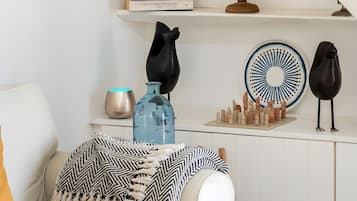 Un salon avec un canapé blanc, un globe terrestre et des objets décoratifs disposés sur des étagères.