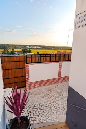 A balcony with a view of a rural landscape, a wooden fence, and a potted plant. - Holiday Home 'Cantinho De São Miguel' with Wi-Fi and Air Conditioning (Alcácer do Sal)