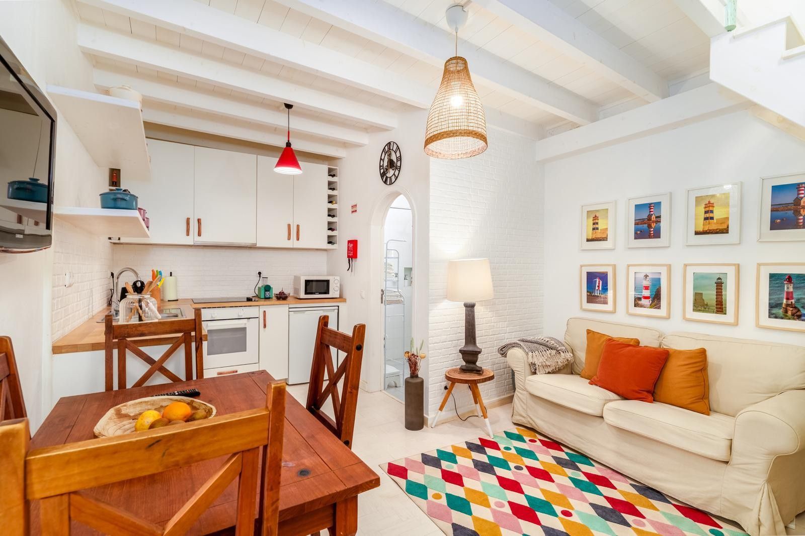 A compact living space with a kitchenette, dining area, and a sofa with a colorful rug.