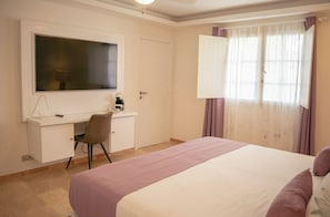 A bedroom with a bed, a desk with a chair, a television, and a window with curtains. - FIESTA TROPICAL playa LOS CORALES (La Altagracia Province)