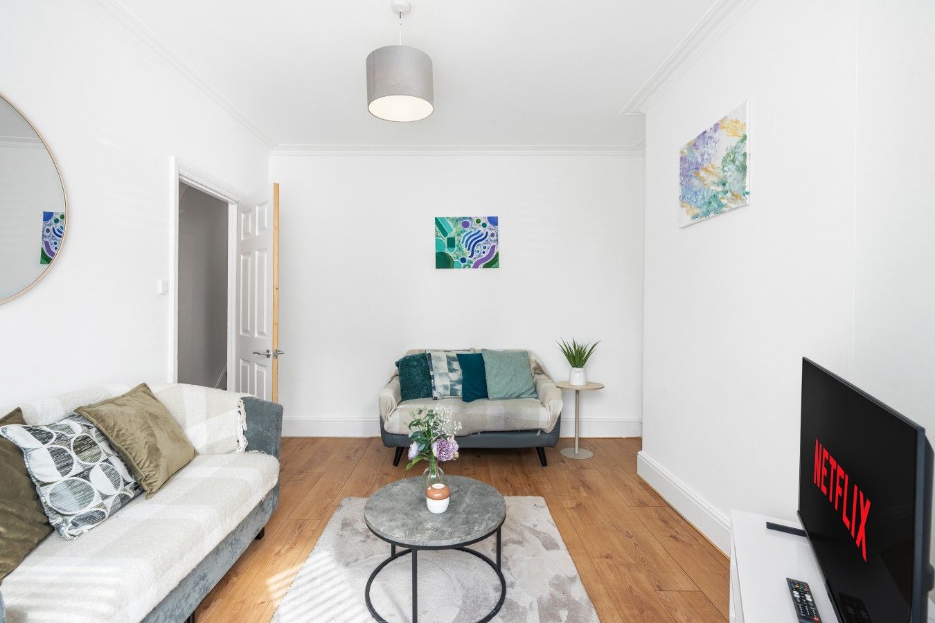 A modern living room with a sofa, a coffee table, a TV, and artwork on the walls.