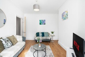 Ett modernt vardagsrum med en soffa, ett soffbord, en tv och konstverk på väggarna.