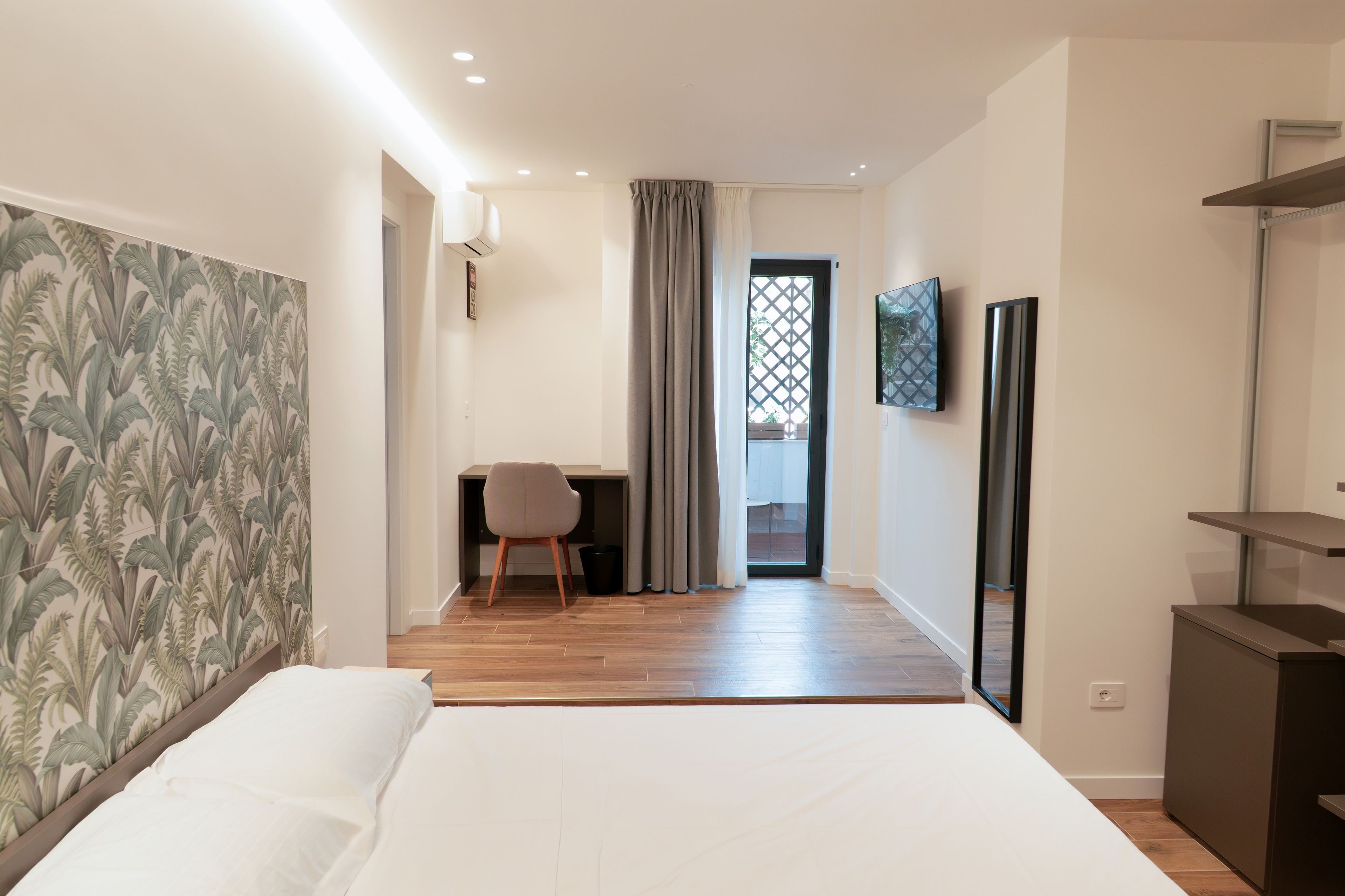 Een hotelkamer met een bed, een bureau, een stoel, een televisie en een spiegel.