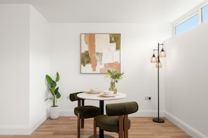Quarto com uma mesa redonda, duas cadeiras, um abajur e um quadro na parede.