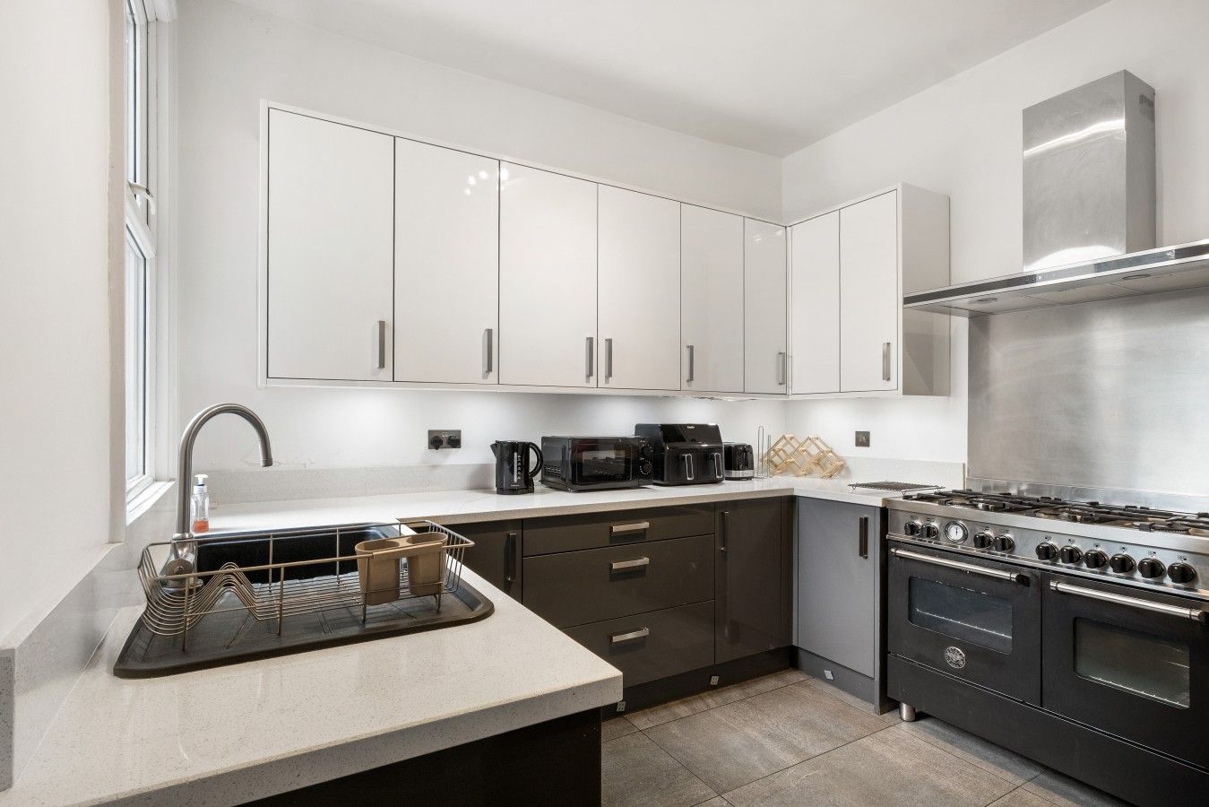 Une cuisine moderne avec des meubles blancs, une cuisinière en acier inoxydable et un four encastré.