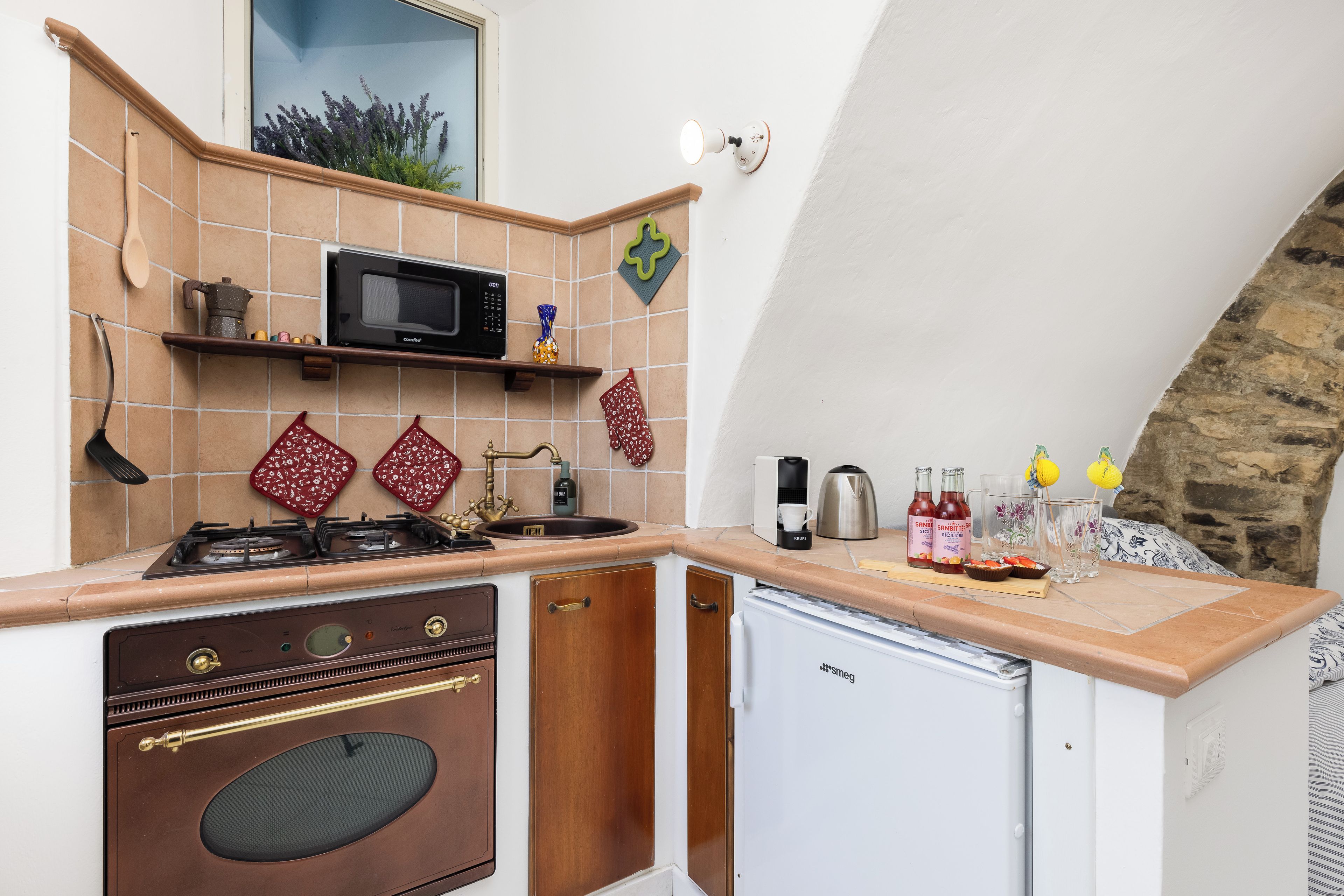 Une cuisine compacte équipée d’une cuisinière, d’un four, d’un four à micro-ondes et d’un petit réfrigérateur.