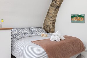 Ein Bett mit einer gestreiften Tagesdecke, einer braunen Decke und zusammengerollten Handtüchern.