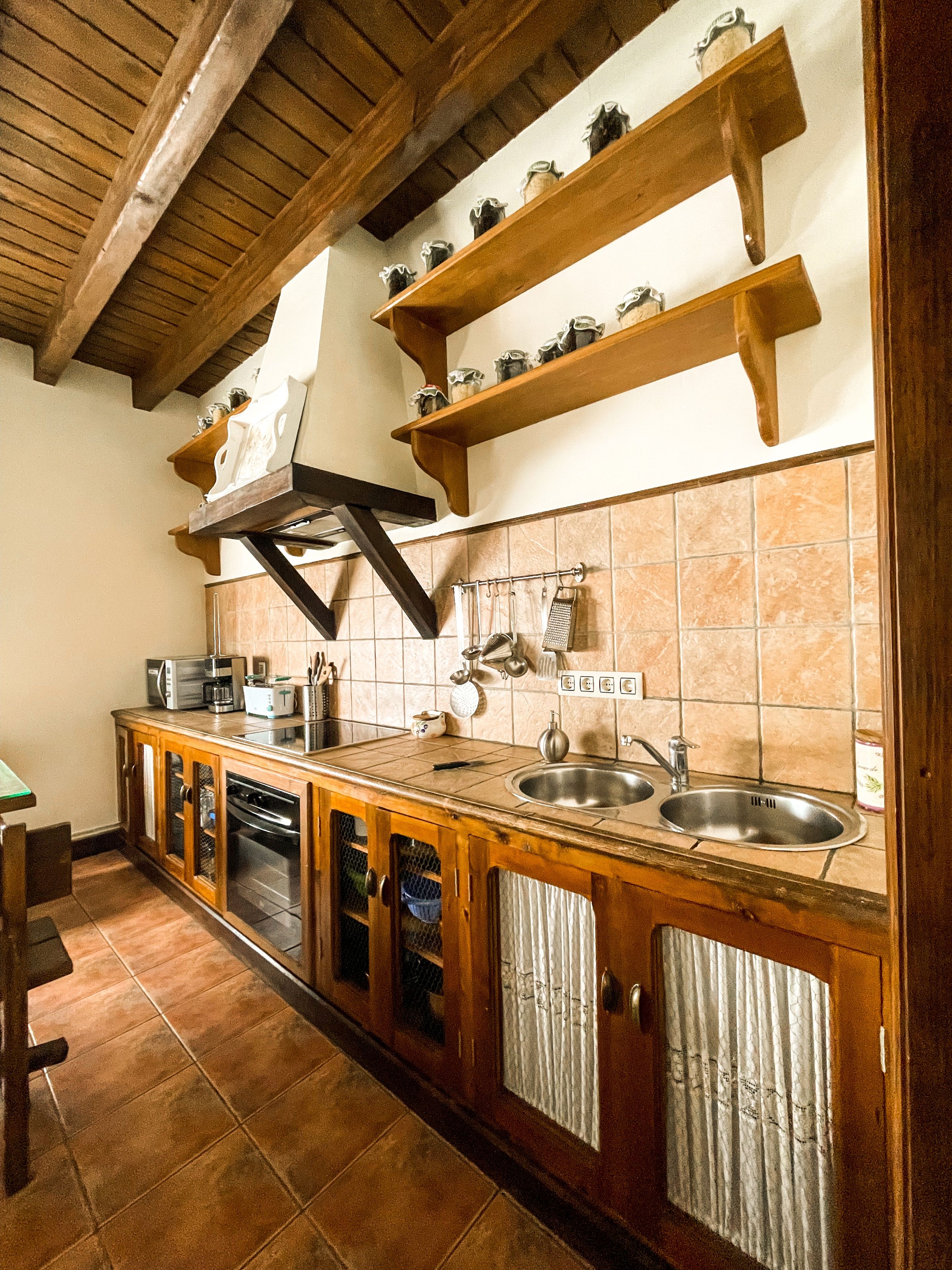 A kitchen with wooden cabinets, a double sink, and a range hood.