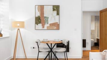 Un comedor moderno con una mesa redonda, dos sillas, una lámpara de pie y un cuadro en la pared.