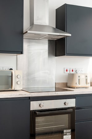 Una cocina equipada con microondas, tostadora, horno y extractor.