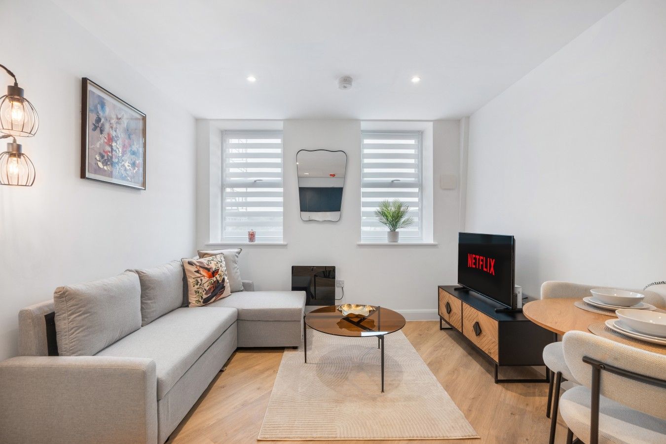 Una sala de estar moderna con sofá, mesa de centro, televisor y comedor.