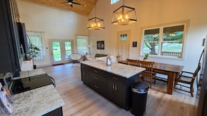 Un'ampia cucina con un'isola grande, pavimento in legno e illuminazione a sospensione.
