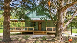 Un rustico chalet con un portico, immerso in alberi secolari.