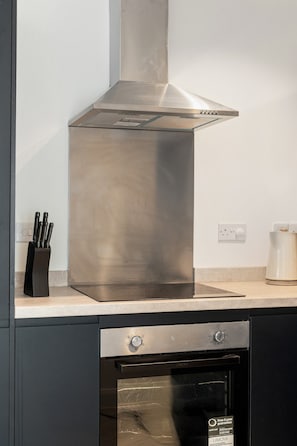 Una campana de acero inoxidable sobre una encimera de cocina con un lavavajillas debajo.