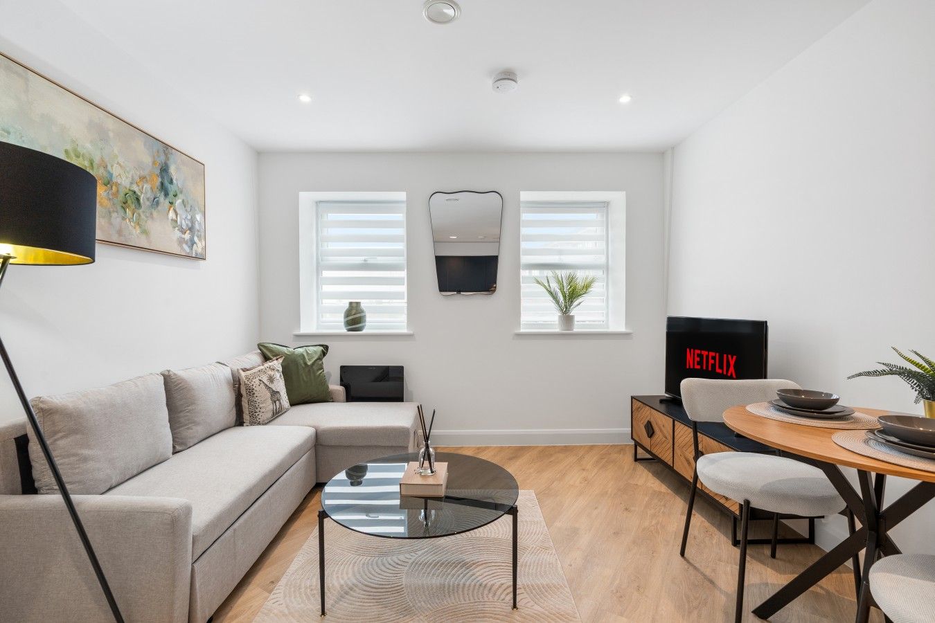 Una sala moderna con sofá, mesa de centro, televisor y zona de comedor.