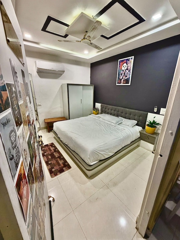 Quarto com cama, mesa de cabeceira, ar-condicionado fixado na parede e ventilador de teto.