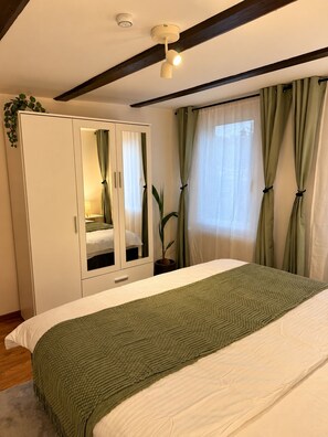A bedroom with a bed, a wardrobe, a ceiling light, and a window with curtains. - Cozy 2-bedroom Apartment in Eriswil (Eriswil)