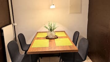 En matplats med ett träbord, fyra stolar, en vas med växter och en hängande lampa.