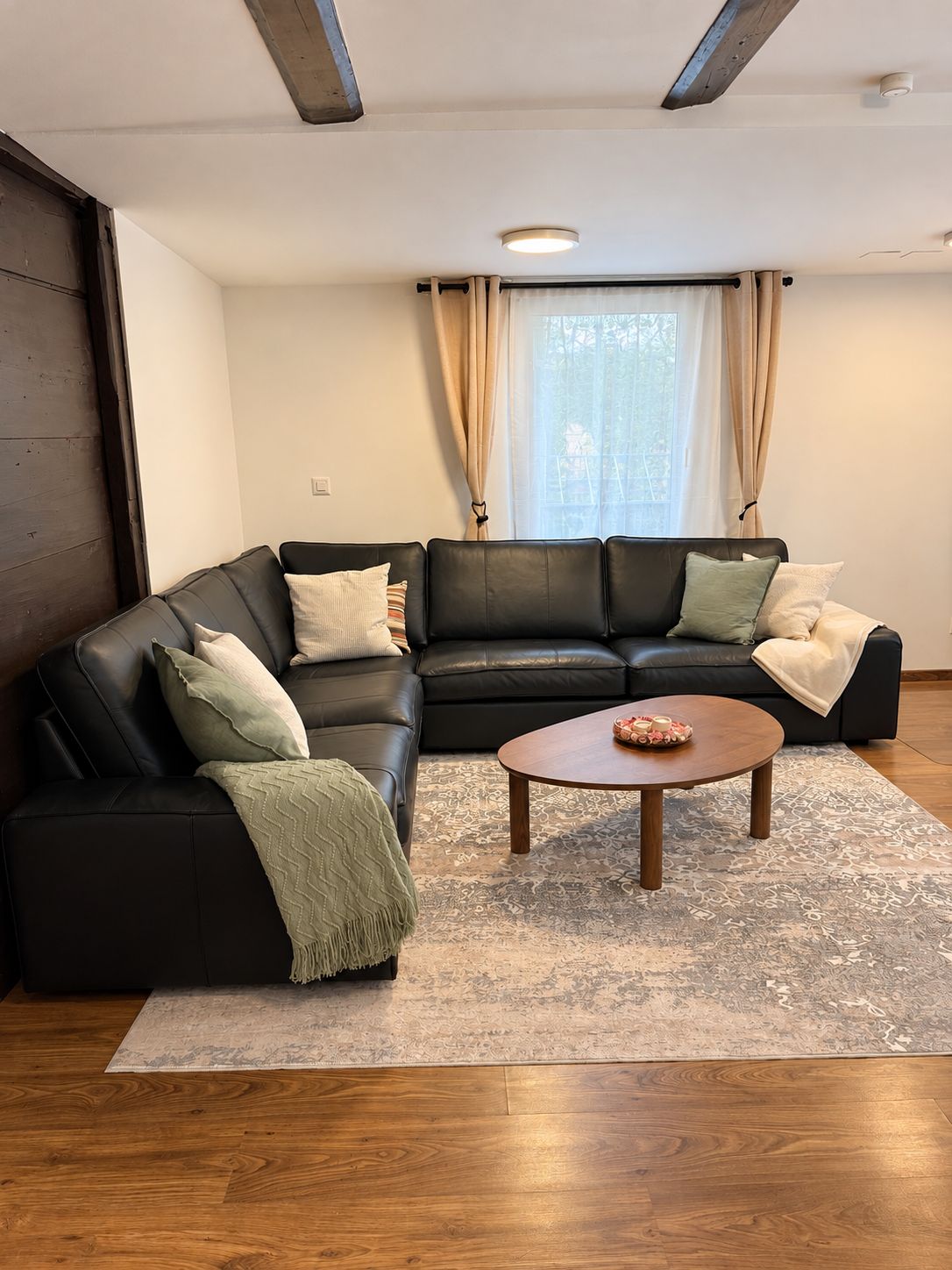 Een moderne woonkamer met een hoekbank, een salontafel en een kamerbreed tapijt.