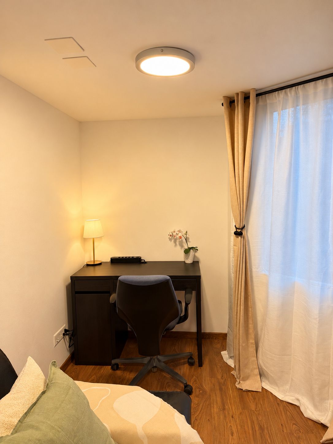 A hotel room with a desk, chair, and a bed.