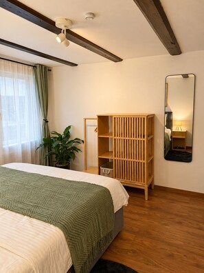 A bedroom with a bed, a wooden wardrobe, a potted plant, a mirror, and a ceiling fan. - Cozy 2-bedroom Apartment in Eriswil (Eriswil)
