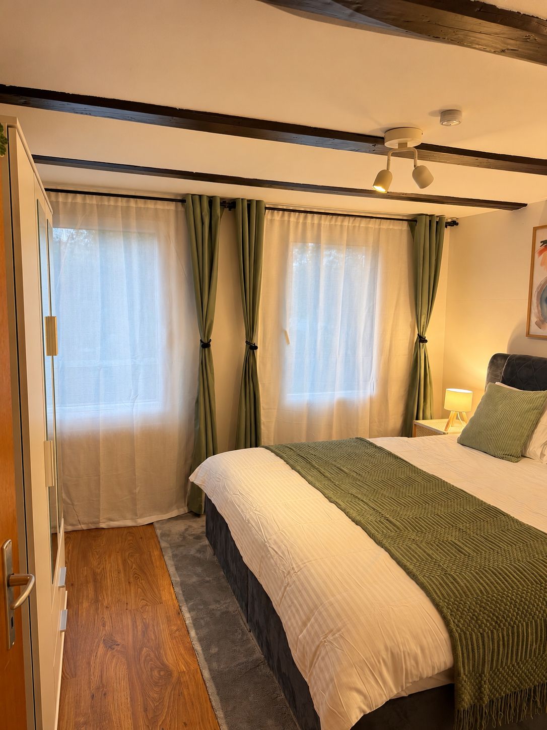 Una camera da letto con un letto, tende, un comodino e una lampada.