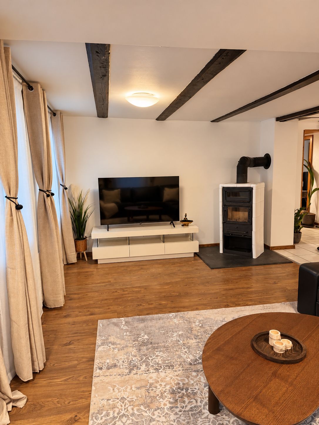 A modern living room with a flat-screen TV, a built-in fireplace, and a round wooden coffee table.