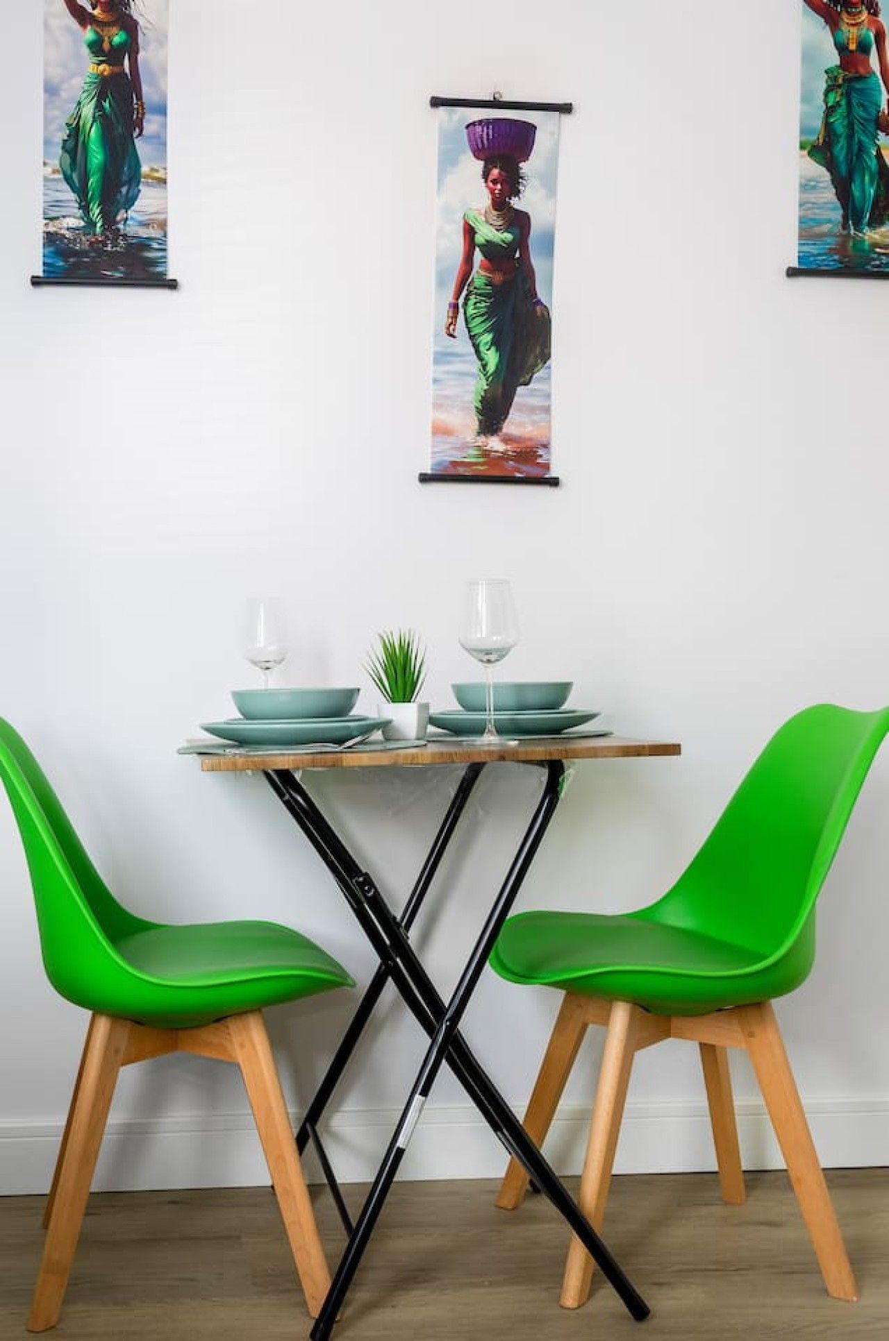 A dining area with a table, two chairs, and a wall-mounted picture.