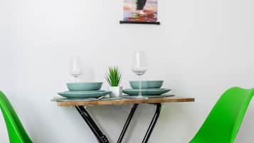 A dining area with a table, two chairs, and a wall-mounted picture.