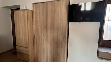 A room with a wooden wardrobe, a white wall, and a window.