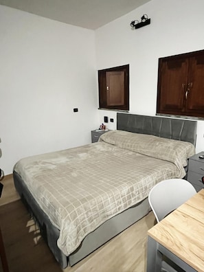 A bedroom with a bed, a bedside table, a chair, and a wooden table.