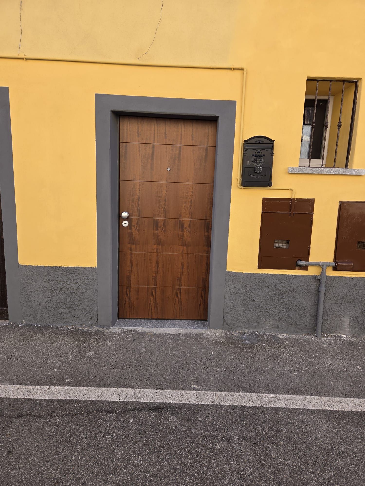 Un bâtiment jaune avec une porte en bois et une boîte aux lettres.