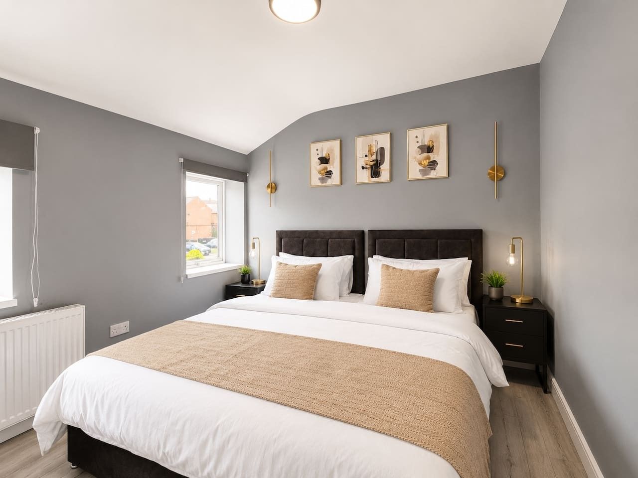 A bedroom with a large bed, bedside tables, a window, and artwork on the wall.