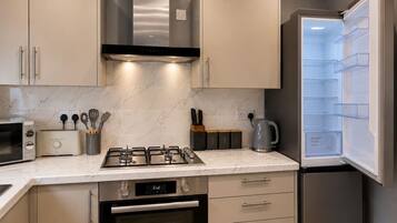A modern kitchen with a built-in microwave, toaster, gas stove, oven, and a refrigerator with a humidity control feature.