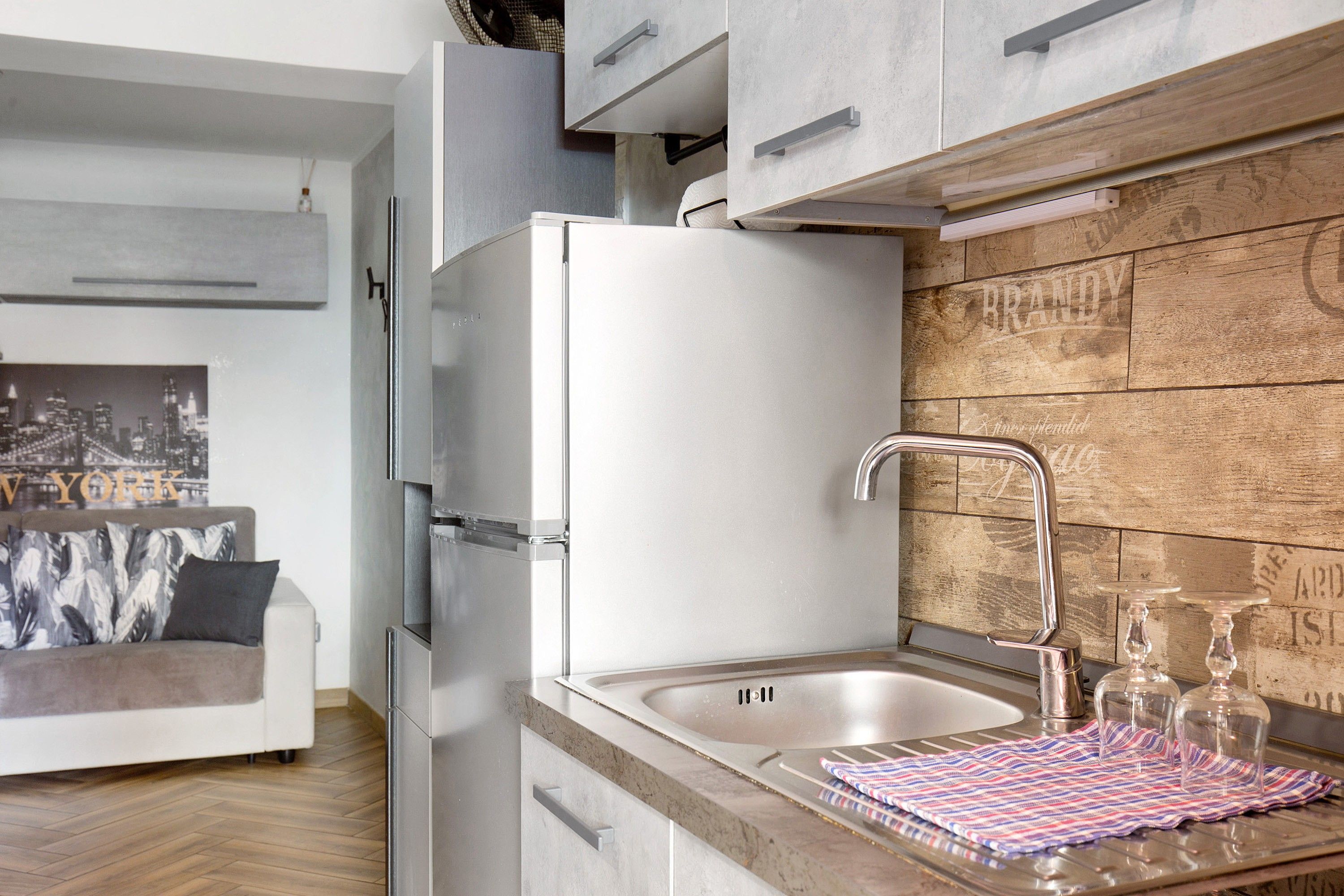 Eine moderne Küche mit integriertem Spülbecken, Edelstahlgeräten und einer Wand in Holzoptik.