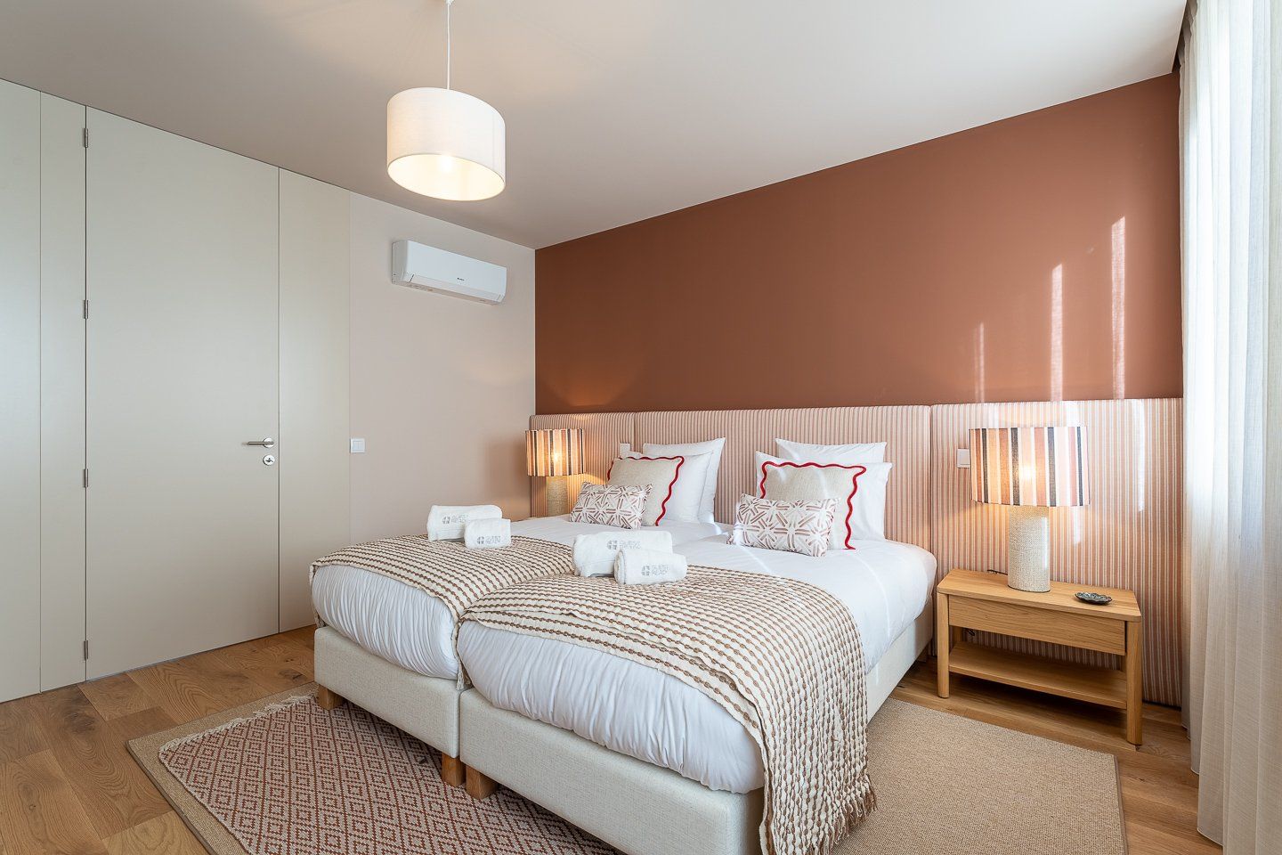 A bedroom with a large bed, bedside lamps, a nightstand, and a wardrobe.