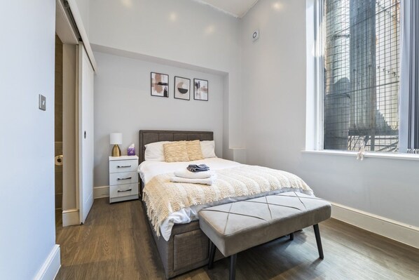 Ein Schlafzimmer mit Bett, Nachttisch, Bank und einem Fenster mit Blick.