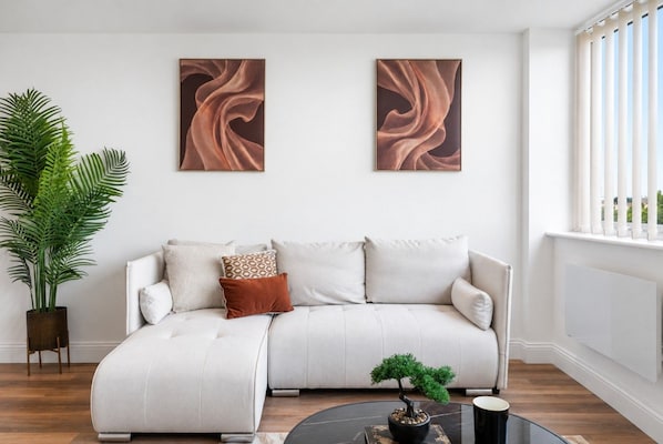 Uma sala de estar moderna com sofá modular, uma planta em vaso e duas pinturas abstratas na parede.