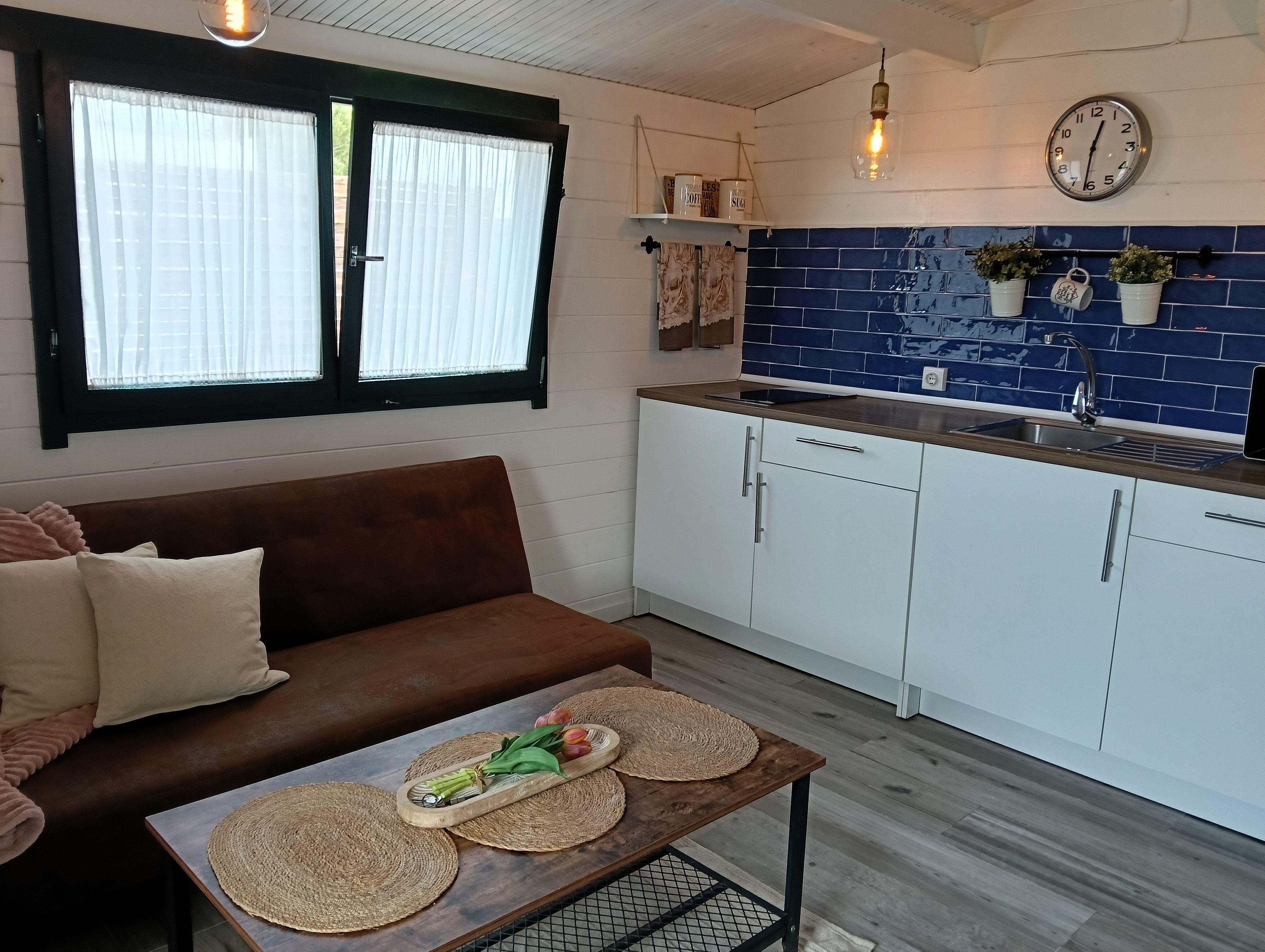 Een moderne keuken met witte kasten, een houten aanrechtblad en een blauwe achterwand.