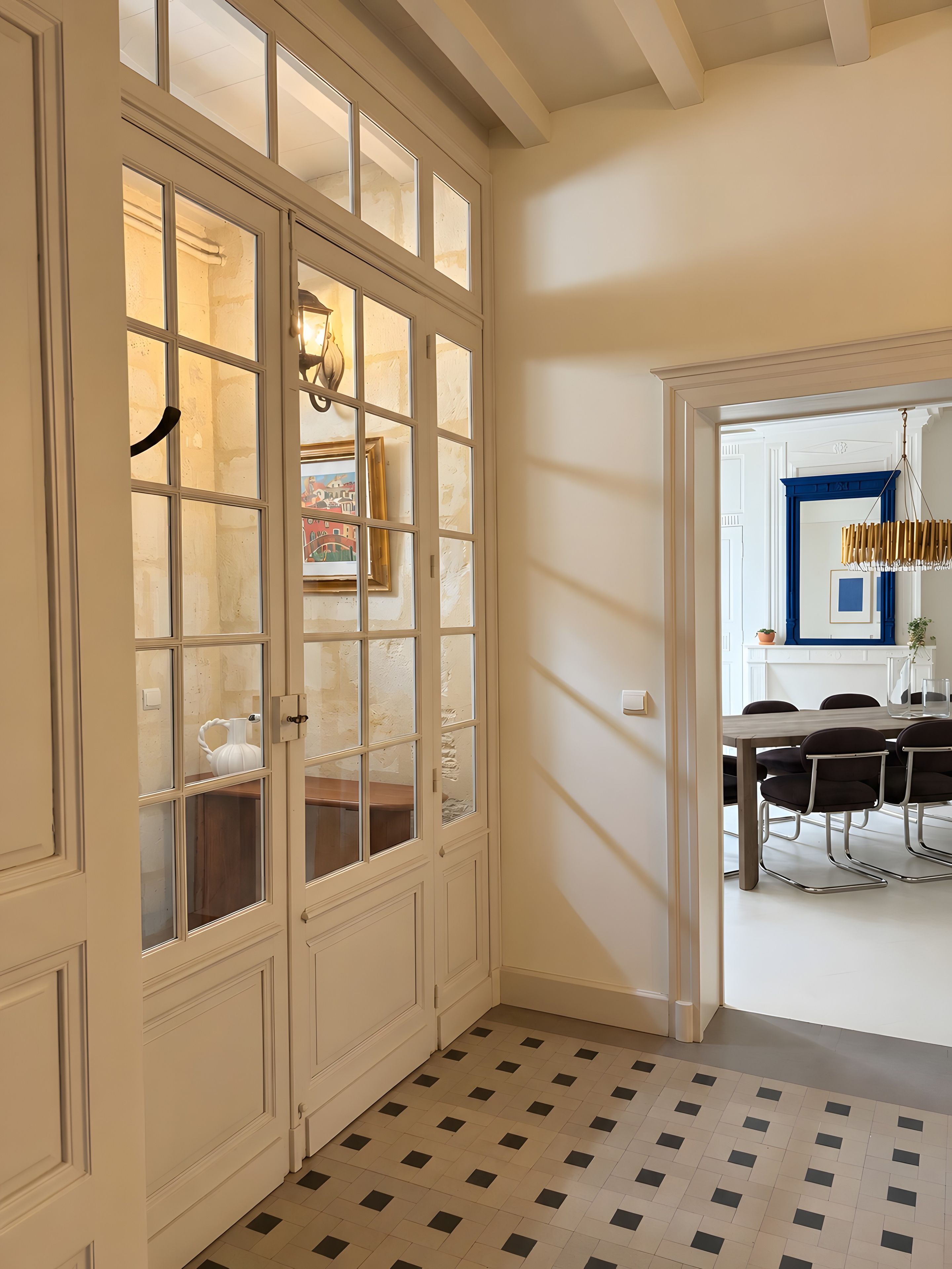 A room with a white door, a tiled floor, and a dining area with a table and chairs.