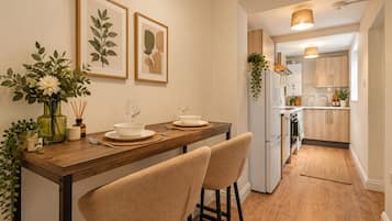 A modern kitchen with wooden cabinets, a built-in oven, and a dining area with a wooden table and two chairs.