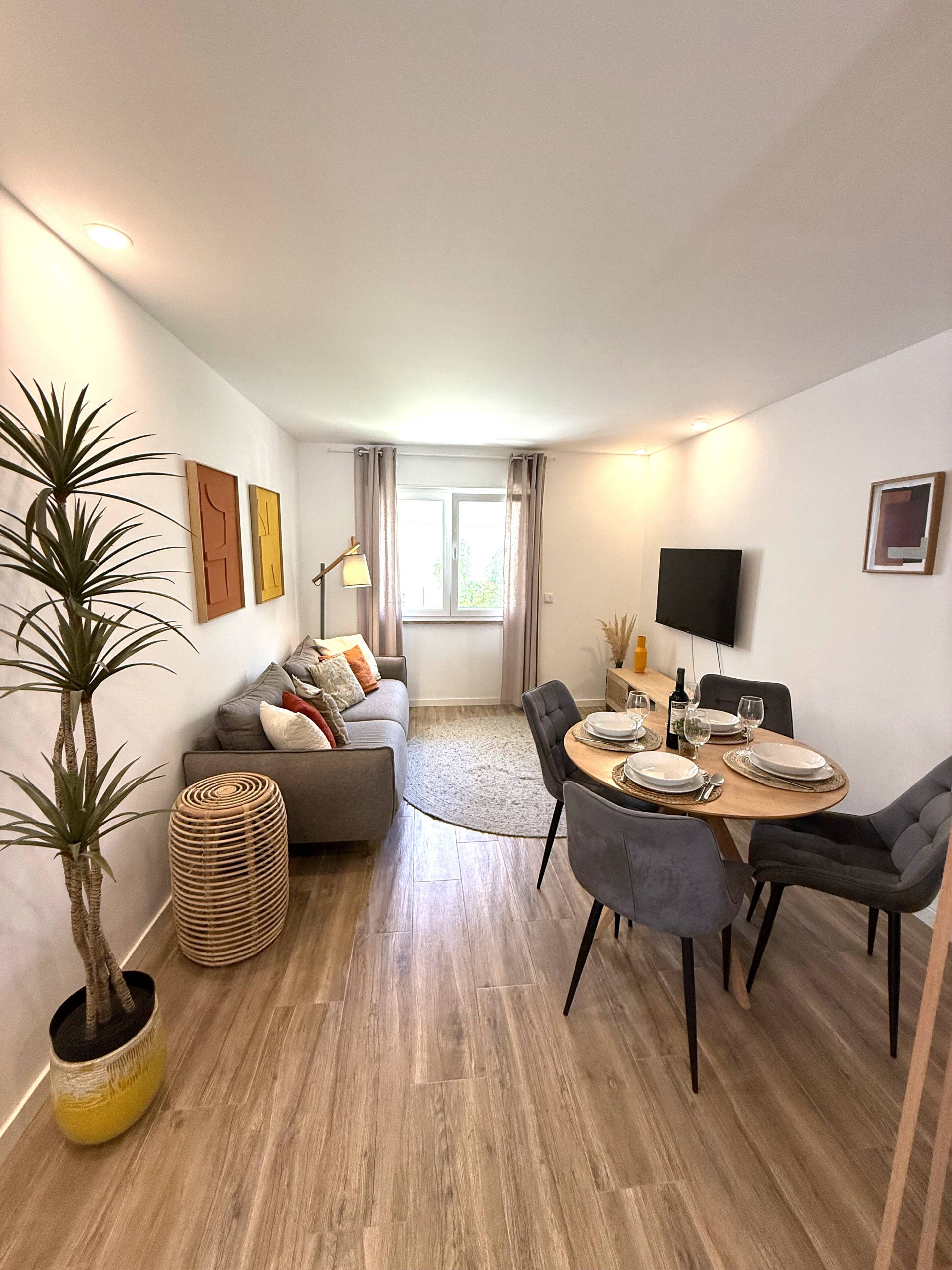 A modern living room with a sofa, dining table, chairs, and a TV.