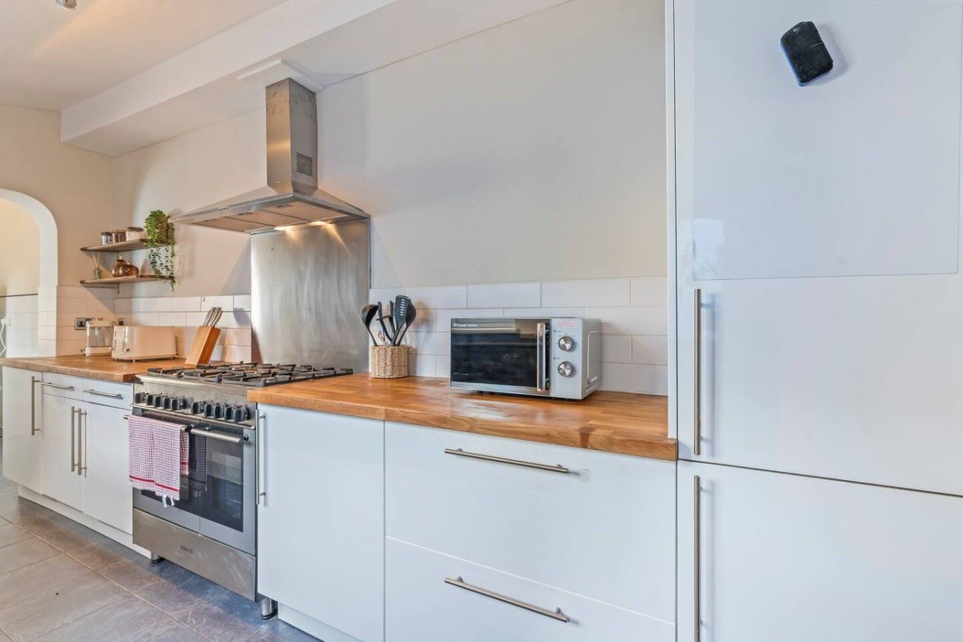 A modern kitchen with white cabinets, a stainless steel range, a built-in oven, a microwave, and a toaster.