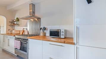 A modern kitchen with white cabinets, a stainless steel range, a built-in oven, a microwave, and a toaster.