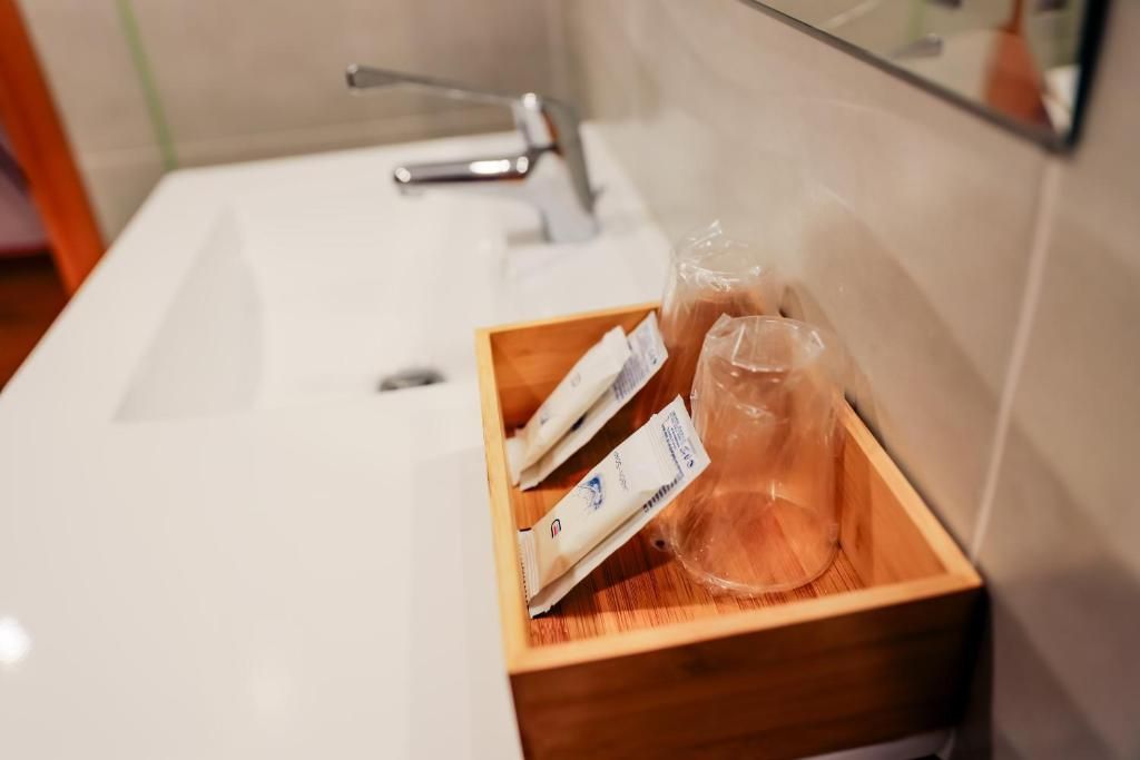 A bathroom sink with a wooden tray holding toiletries and a plastic bottle.